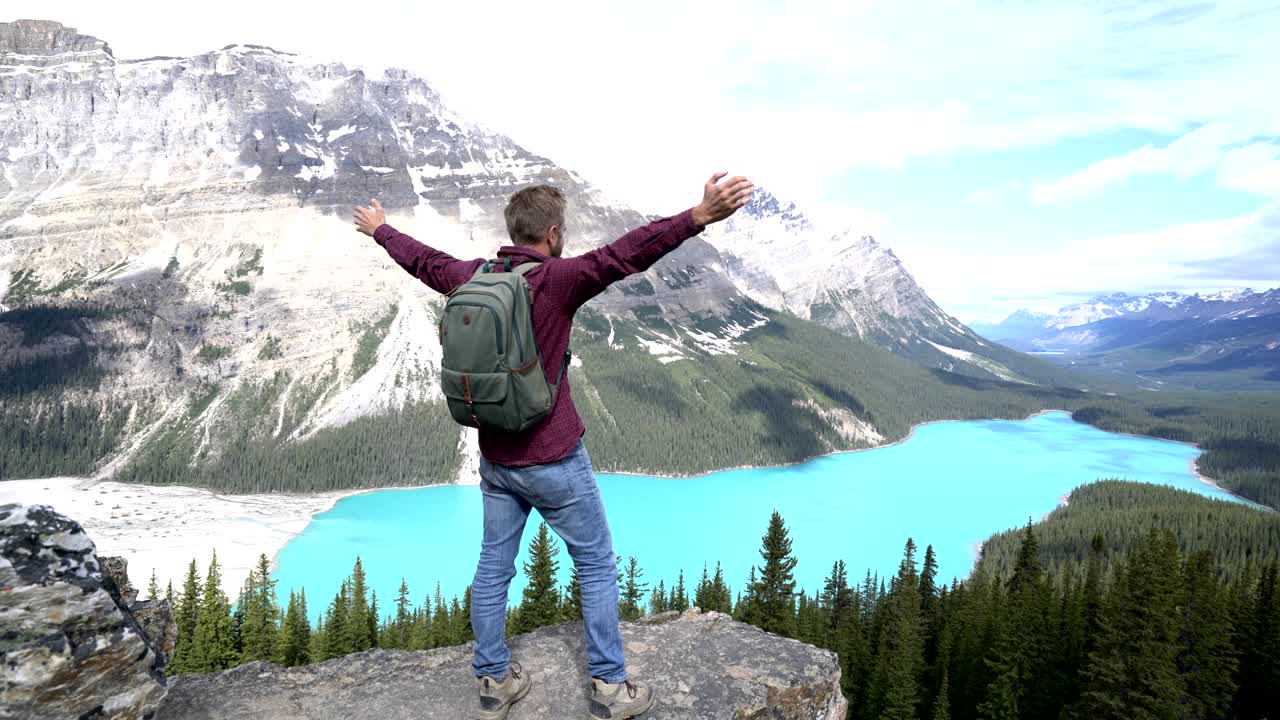 el hombre exitoso llega a la cima de la montaña, extiende los brazos abiertos, canadá