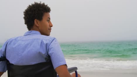 Rückansicht-Eines-Afroamerikanischen-Mannes,-Der-Im-Rollstuhl-Am-Strand-Sitzt-4k
