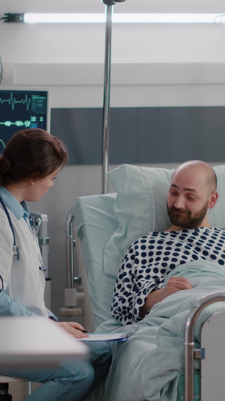 Vertical video: Black nurse checking patient vitals monitoring heart rate injecting vitamin