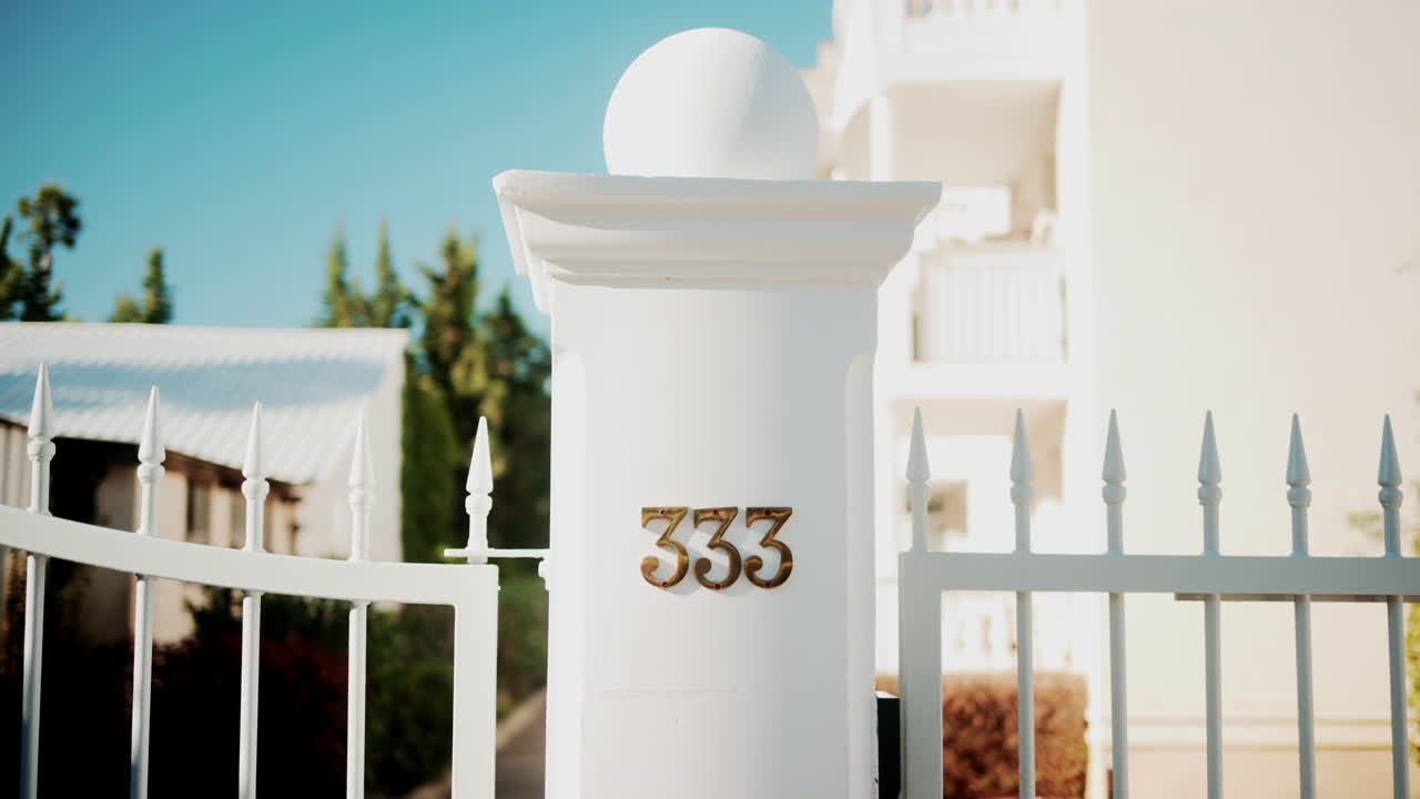 Golden metallic number 333 mounted on a white wall in sunlight