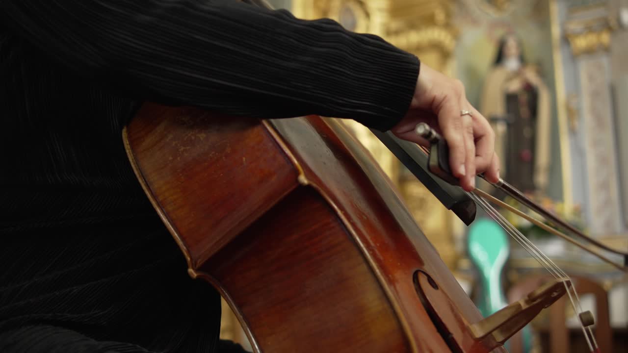 Close up of a musician playing cello with a bow in a classical setting