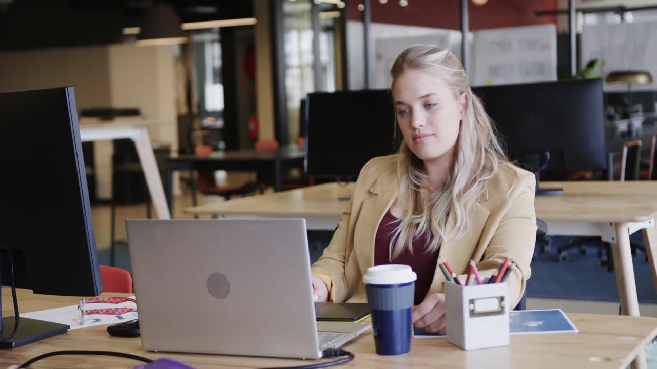 Happy caucasian casual businesswoman in wheelchair using tablet in office, in slow motion