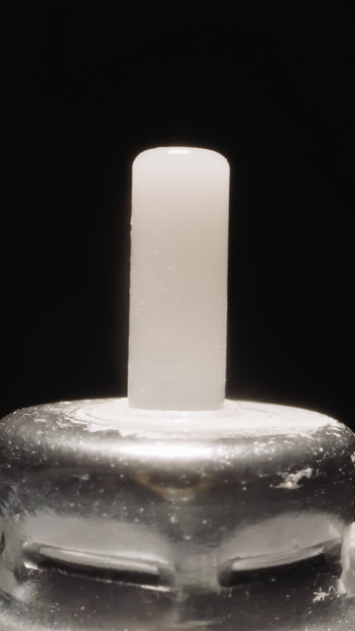 Plastic tip on metal cap of inhaler bottle shining at bright studio light. Container designed for liquids and fluids turning on black background macro