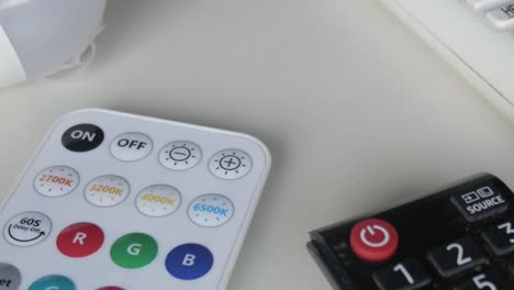 detailed view of different remote controls placed on a white surface, panning left to reveal their buttons and details