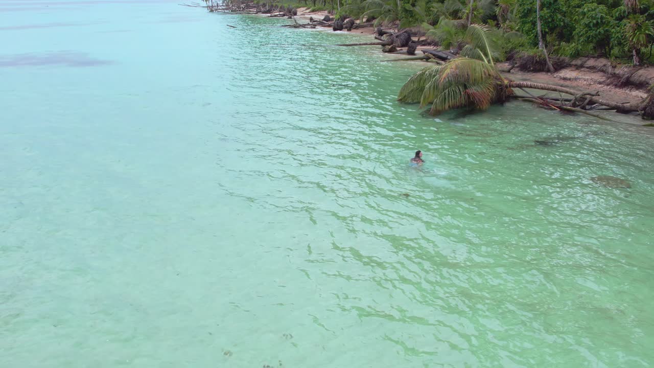 Vista orbital de dron de una niña nadando en la playa Zapatilla Cay en Bocas del Toro, Panamá_4K