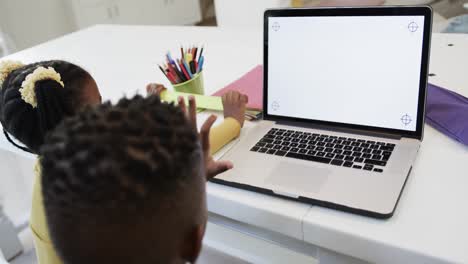 african american brother and sister in online class using laptop with copy space, slow motion