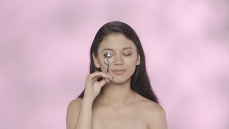 mujer aplicando rizador de pestañas