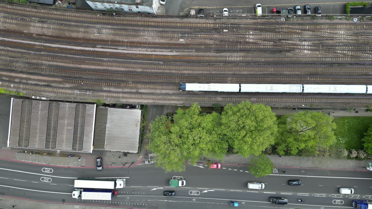 Calm 4K drone shot hovering over trains and cars passing through London. Slow motion capable, ideal for urban, travel, lifestyle, or cinematic city projects
