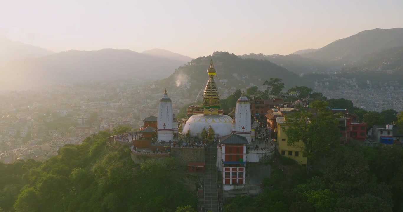 Ripresa con drone in orbita che circonda il Tempio delle Scimmie di Swayambhunath durante l'ora d'oro, con vista sulla Valle di Kathmandu e sulla circostante foresta verde in Nepal, con la città