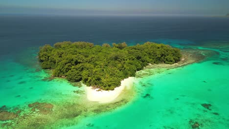 A-drone-flies-over-a-lush-green-island-revealing-a-coral-reef-at-Port-Olry-on-the-island-of-Espiritu-Santo