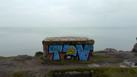 aerial view of abandoned seaside fortification bunker at karosta northern forts on the beach of baltic sea in liepaja in overcast spring day, close flyover revealing drone shot moving backwards