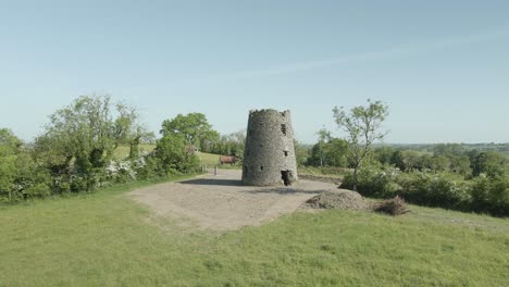 ruined medieval celtic round tower in green field, midlands, ireland - aerial drone shot