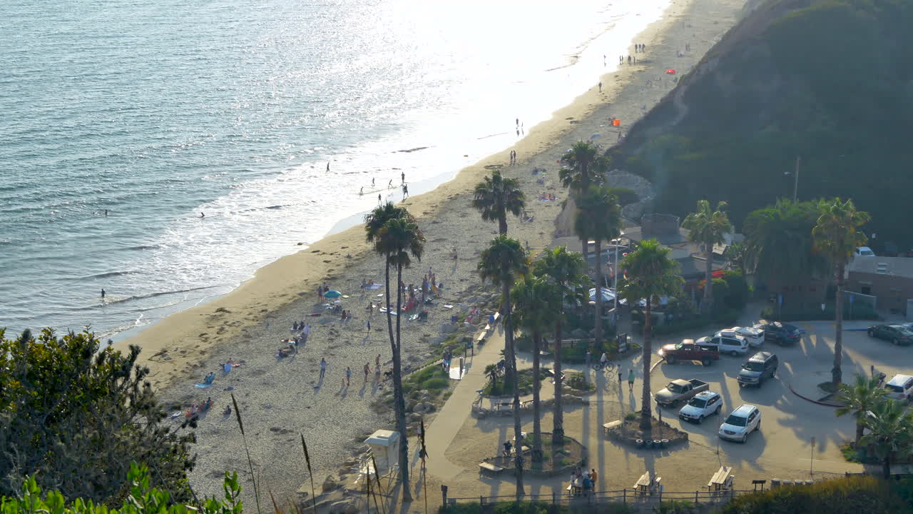 캘리포니아주 산타바바라에 있는 헨드리스 해변에서 사람들이 해변에서 노는 사람들과 푸른 태평양이 내려다보이는 절벽에 서서