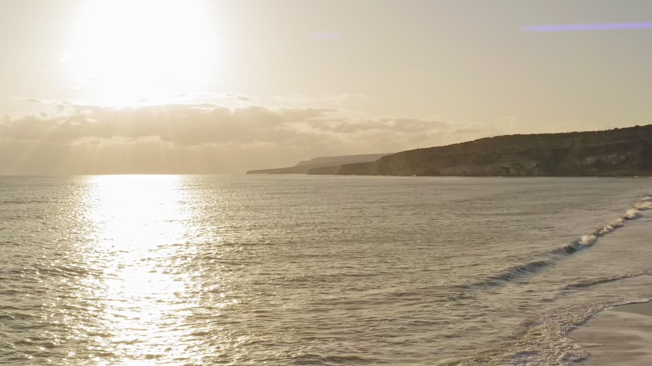 cinematic shot of drone flying towards the horizon over the ocean as the sun rays reflect off the surface
