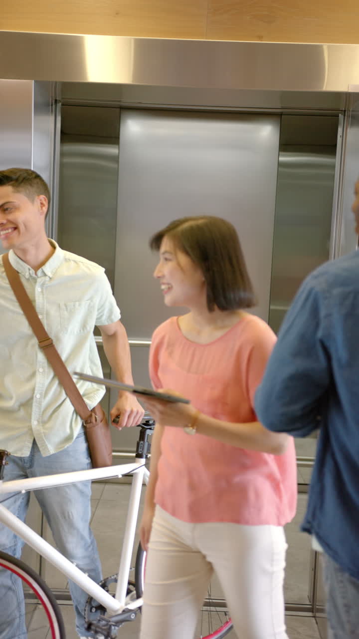 Vertical video: Waiting for elevator, man in denim jacket standing near bicycle in building