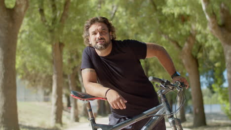 tired man with disability standing with elbow on bike seat