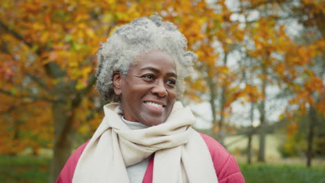 head and shoulders portrait of senior woman on walk through autumn countryside - shot in slow motion