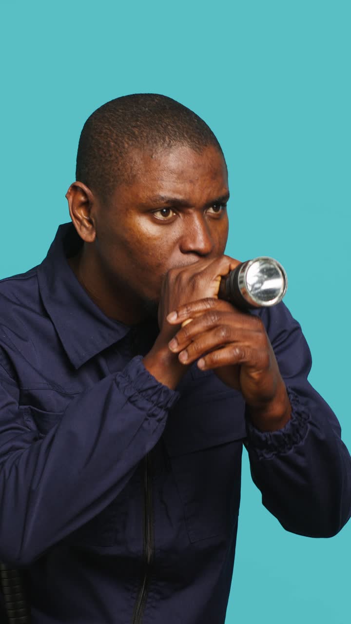 African Man Cautiously Searching with a Flashlight
