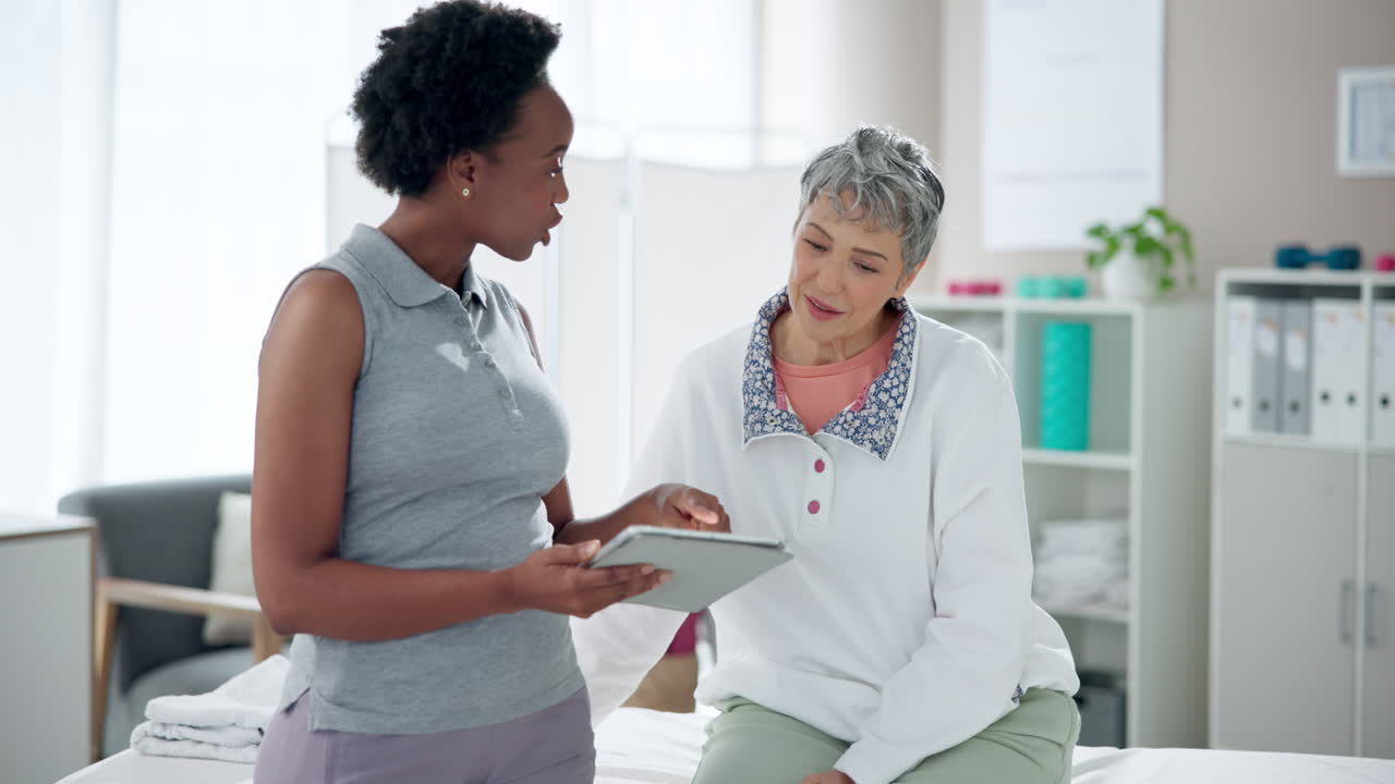 Physical therapist consulting with senior woman using a tablet