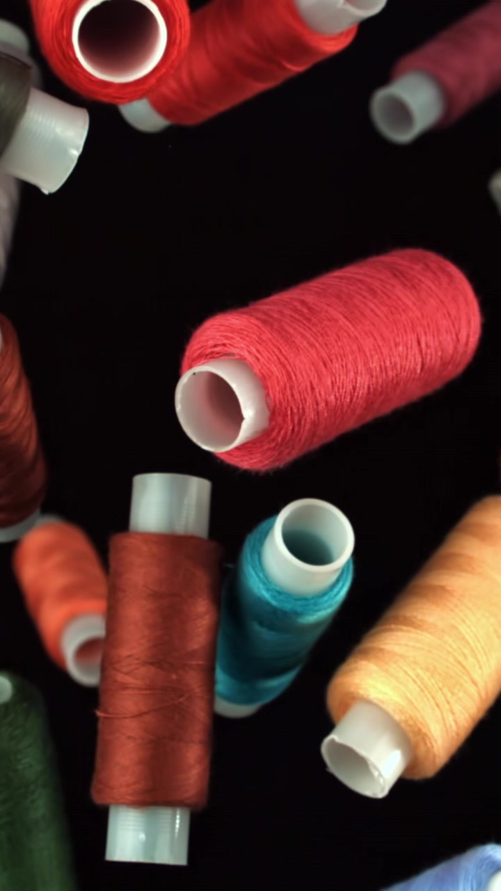 Colorful Spools of Thread Falling in Slow Motion Against a Black Background
