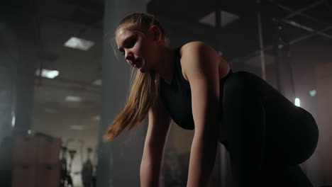 A-woman-does-stretching-exercises-in-a-dark-fitness-room-after-a-workout-Fitness-woman-working-out-on-core-muscles-at-dark-gym