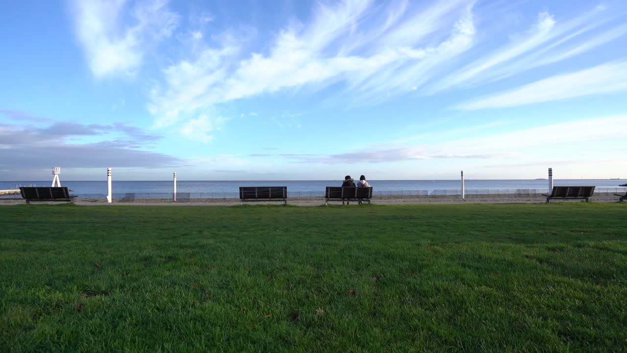 두 소녀는 화창한 날 해변 앞 벤치에 앉아 넓은 정적인 벨뷰 스트랜드 덴마크