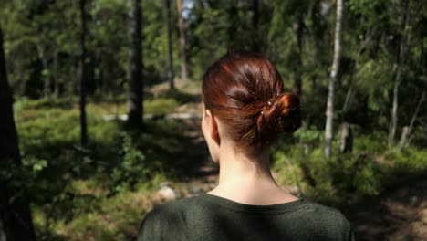 woman walking forest path slowly, nature walk, back view close up