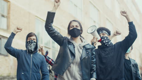 caucasian woman in facial mask yelling with arms up in a protest with multiethnic group of people in the street