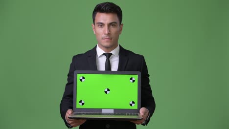 joven y guapo hombre de negocios hispano contra un fondo verde