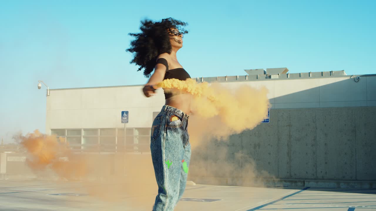 Young woman dancing outside with smoke grenade at sunset on rooftop parking garage
