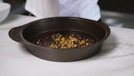 Female-hands-pouring-dough-into-round-baking-dish.-Cheesecake-ingredients.-Cake-dough-pouring-in-baking-pan.-Chef-pours-dough-in