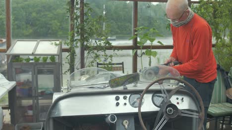 a man polishes the body of a vintage buckler car