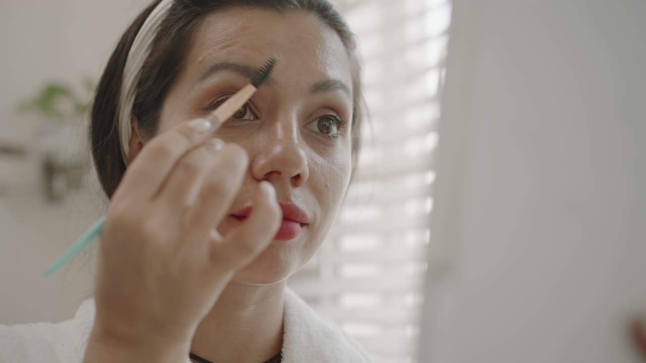 Caucasian Woman Looking at Mirror when Shaping Eyebrows