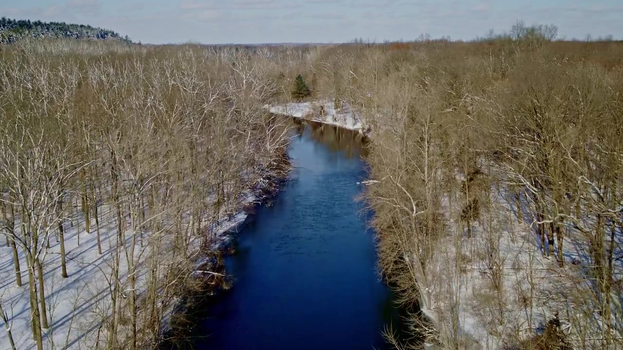 Matalalla lentävä drone kuvaa talvisia maisemia Huron-joen yllä matkalla Dexteriin, Michiganiin