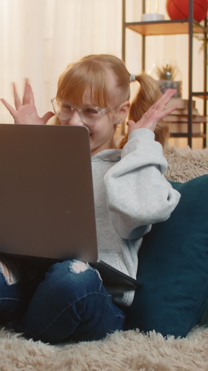 Young teenager girl laptop video call online chat at home sofa wave silly laughs funny faces energy