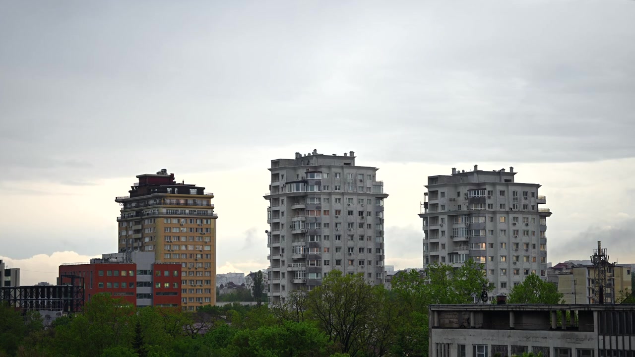 Timelapse de edificios residenciales modernos erigiéndose frente a nubes en movimiento, presentando un paisaje urbano tranquilo con arquitectura urbana contemporánea.