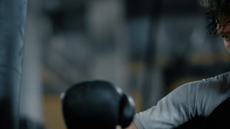 Angry-fighter-doing-workout-in-sport-club.-Kickboxer-hitting-boxing-bag-at-gym