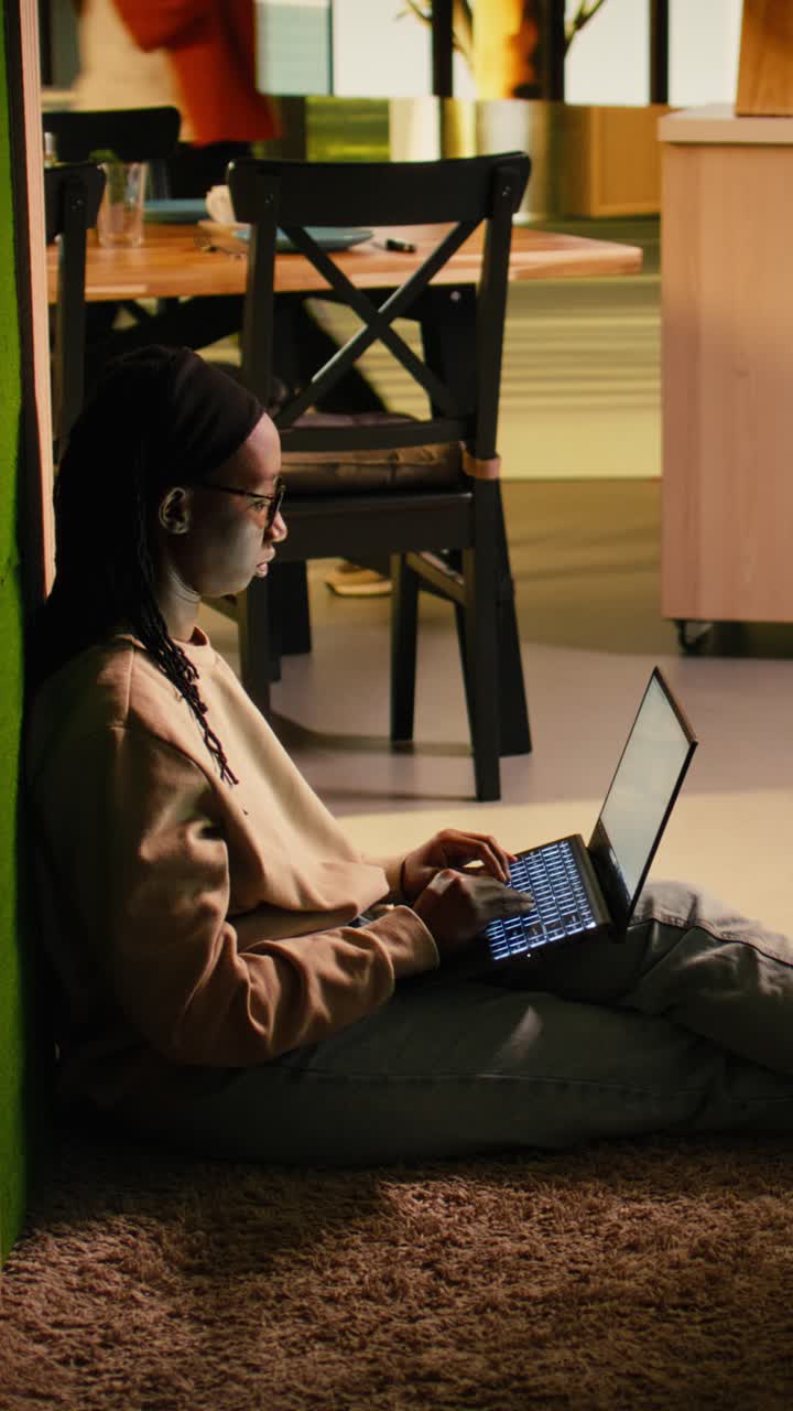 Vertical Video Black female adult, browsing on laptop, cozy moment, on floor hallway