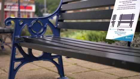 Social-distancing-sign-on-empty-city-bench-wide-shot