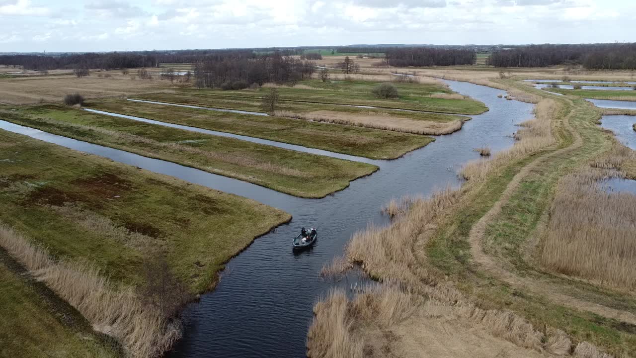 observa cómo un barco navega con gracia por las aguas tranquilas, rodeado de exuberante vegetación y encantadores paisajes rurales