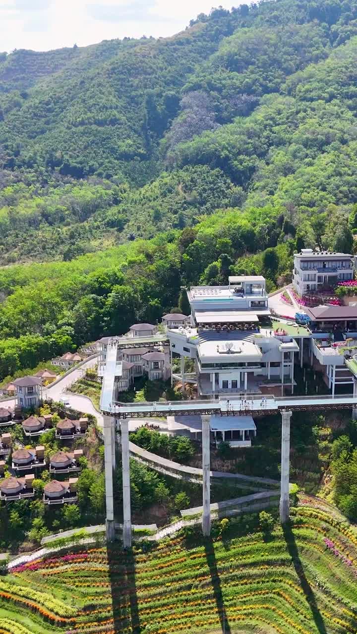 Drone footage captures a scenic resort nestled in lush greenery and hills in Phuket, Thailand, showcasing modern architecture and natural beauty