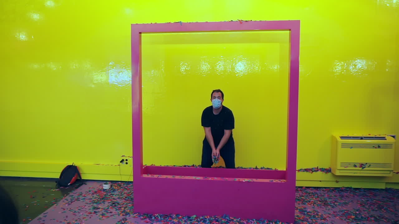 프레임에 서 있는 마스크를 쓴 남자가 공중에 색종이 조각을 던졌습니다.