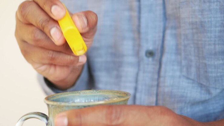 A man adds sugar to his cup of tea.