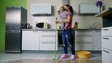 mother mopping the floor and dancing holding baby