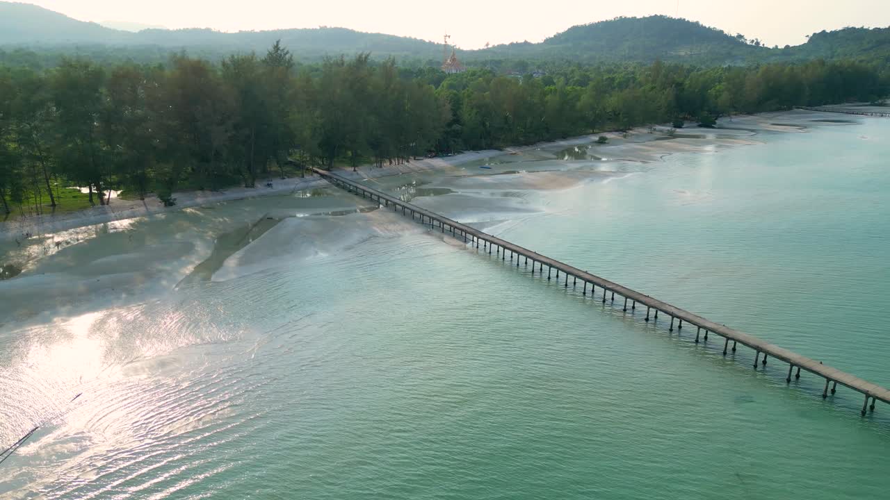Aerial View of a Long Pier Extending into Turquoise Waters along a Tropical Coastline