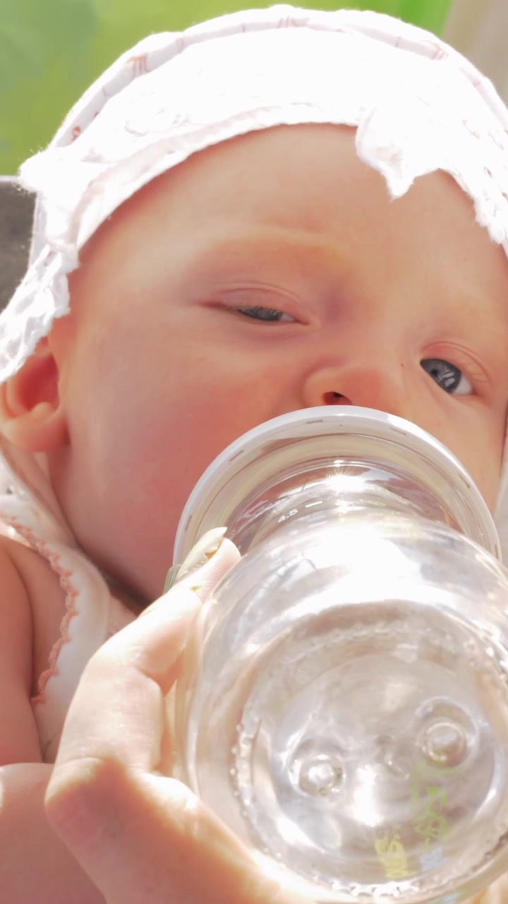 Bambina che beve acqua dal biberon all'aperto