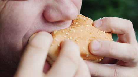 mouth of an adult male greedily eating a hamburger close-up shot