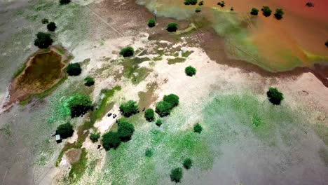 Motociclistas-Activos-Reunidos-A-La-Sombra-De-Las-Acacias-Alrededor-Del-Lago-Magadi-En-El-Gran-Valle-Del-Rift,-Kenia,-áfrica