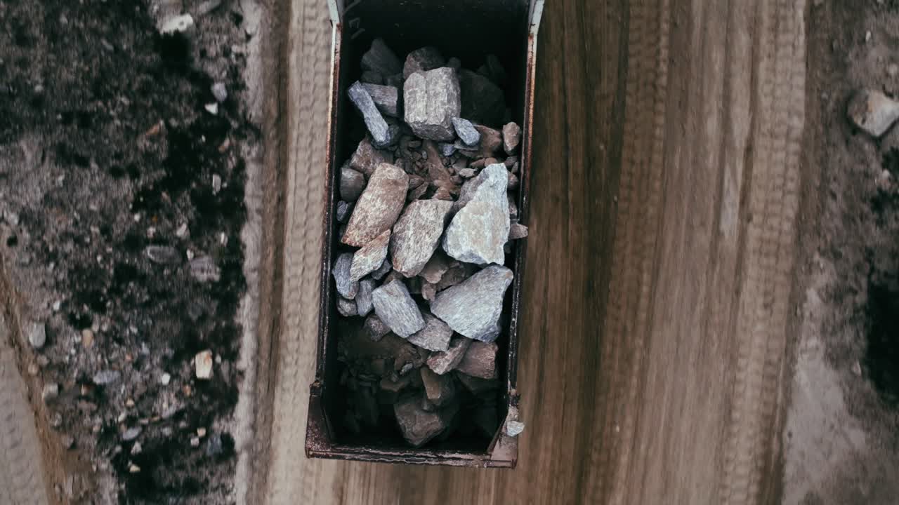 An aerial view of heavy rocks being transported in a large dump truck.