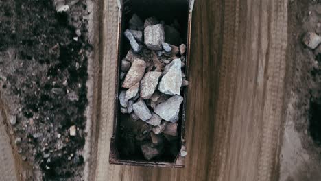 an aerial view of heavy rocks being transported in a large dump truck.